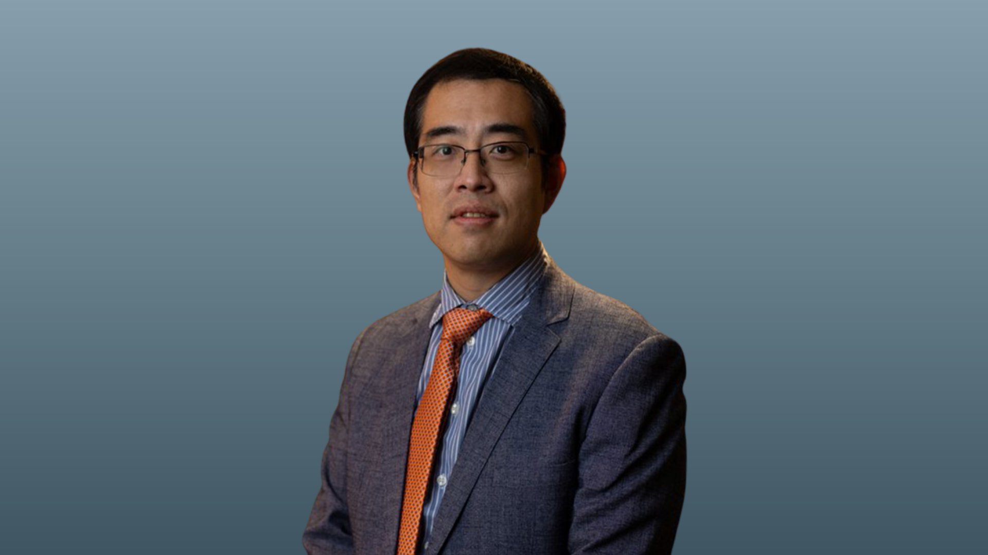 Xiaoqian Jiang, PhD, in a grey suit with orange tie