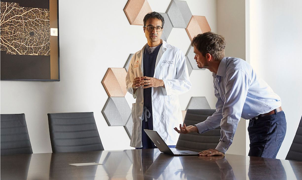 Physician and main in suit discussing inside of a conference room